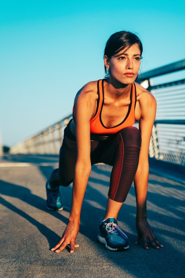 Portrait of young fit woman in sportswear exercising in city to stay healthy. People sport concept